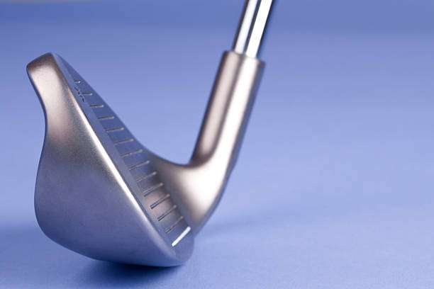 Close-up of a shiny silver golf club head against a light blue background.