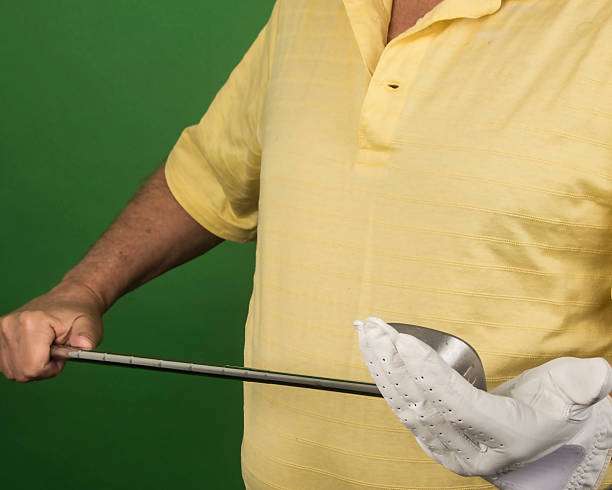 Man in yellow shirt gripping a golf club while wearing a white golf glove.
