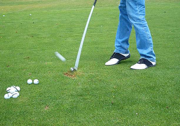 Golfer hitting a golf ball with golf clubs on a grassy field.