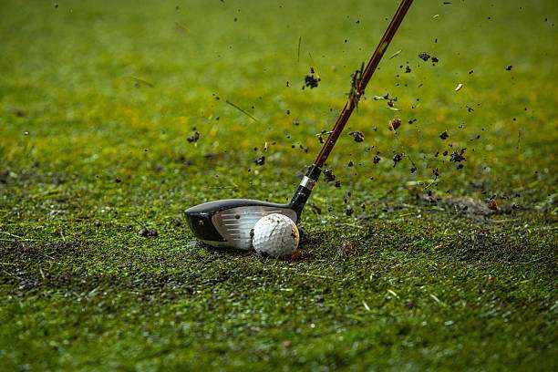 Golf club hitting ball, grass flying, golf clubs in action.
