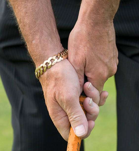 Close-up of a golfer's hands firmly gripping a golf club on the course.