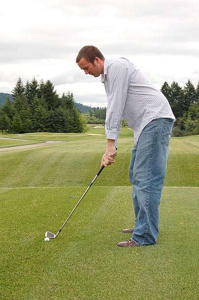Man preparing to hit a golf ball with golf clubs on a course.
